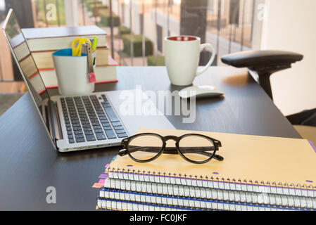 L'espace de travail en fonction, lunettes, portables, ordinateur portable, souris, tasse de café Banque D'Images