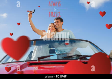 Composite image of cheerful couple standing in red cabriolet Prendre photo Banque D'Images