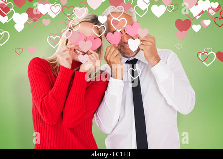 Image composite de silly couple holding cœurs sur les yeux Banque D'Images