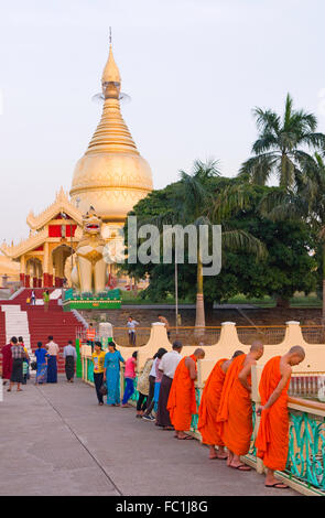Peering moines sur un pont à Maha Wizaya Pagode, Yangon, Myanmar Banque D'Images