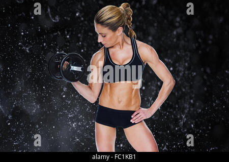 Image composite de femme bodybuilder holding grand noir avec haltère jusqu'à bras regardant biceps Banque D'Images