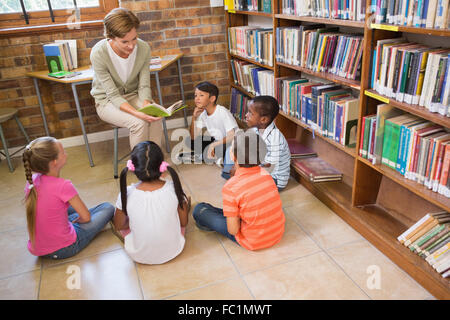 Les élèves et l'enseignant ayant mignon en classe library Banque D'Images