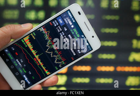 L'utilisation d'un investisseur téléphone mobile pour afficher des informations relatives aux actions en bourse à Huaibei, la province de l'Anhui, est de la Chine le 20 mai 2016. Shanghai Composite Index a diminué de 31,3 points ou 1,04 % à 2976.44 Le mercredi 20 janvier à partir de 3007.74 dans la précédente séance de négociation. Avec le recul, l'indice composite de Shanghai a perdu 6,20  % 196,6 points ou au cours des derniers 12 mois à partir de 3 173,05 points en Janvier de 2015. Banque D'Images