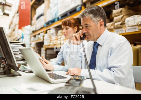 Manager working on laptop phone at desk Banque D'Images