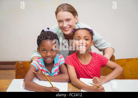 Élèves et professeur Cute smiling at camera in classroom Banque D'Images