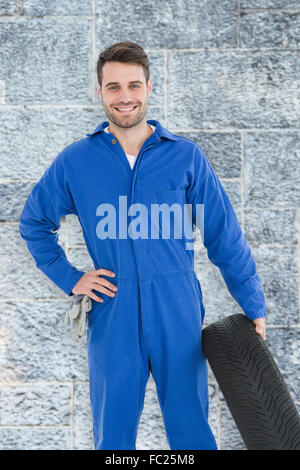 Portrait of male mechanic holding tire Banque D'Images