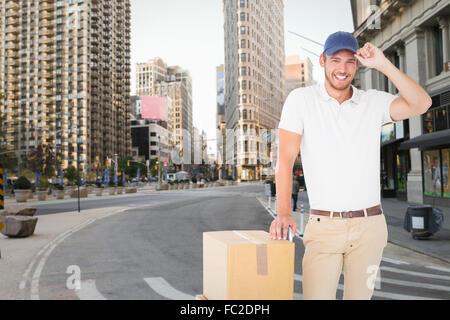 Composite image of delivery man leaning on trolley de boîtes Banque D'Images