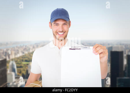 Composite image of delivery man Holding boîte en carton et presse-papiers Banque D'Images