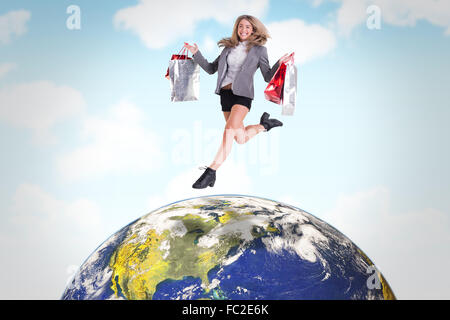 Image composite de saut blonde fête with shopping bags Banque D'Images