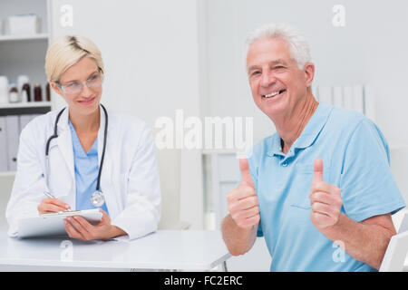 Senior patient gesturing Thumbs up par médecin en clinique Banque D'Images