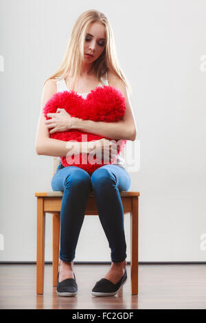 Broken Heart Love concept. Triste Malheureux hugging woman sitting on chair coeur rouge Banque D'Images