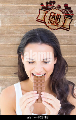 Image composite de jolie brunette eating barre de chocolat Banque D'Images