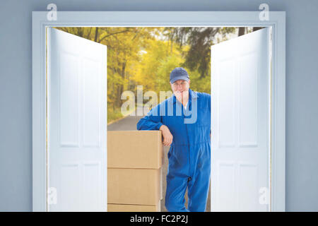 Composite image of delivery man leaning on pile de boîtes de carton Banque D'Images