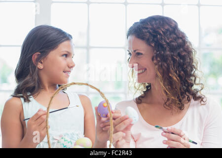 Happy mother and daughter painting Easter eggs Banque D'Images