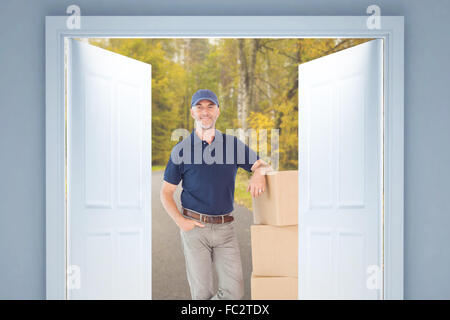 Composite image of delivery man leaning on pile de boîtes de carton Banque D'Images