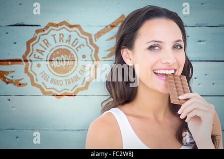 Image composite de jolie brunette eating barre de chocolat Banque D'Images