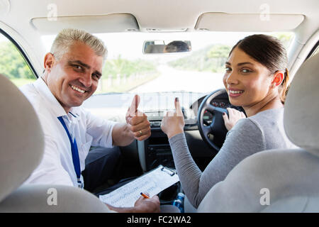 Femme heureuse de prendre des leçons de conduite de l'instructeur et giving Thumbs up Banque D'Images