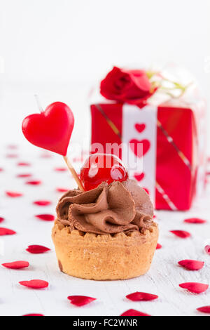 Cupcake chocolat avec cherry en face de boîte-cadeau blanche sur fond de bois. La Saint-Valentin et l'amour gratuit. Banque D'Images