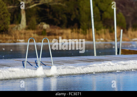 Une piscine ou baignade dock pier a gelé dans la glace de mer à l'hiver. Vu de la mer avec la terre en arrière-plan. H Banque D'Images