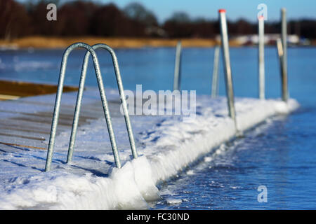 Une piscine ou baignade dock pier a gelé dans la glace de mer à l'hiver. Vu de la mer avec la terre en arrière-plan. H Banque D'Images