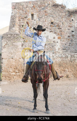 Un Mexicain charro ou pratiques cowboy roping compétences avant une Charreada compétition à une hacienda ranch dans Alcocer, au Mexique. La Charreada est une forme traditionnelle mexicaine de rodeo et teste les compétences de l'équitation à cowboy au lasso, et le contrôle du bétail. Banque D'Images