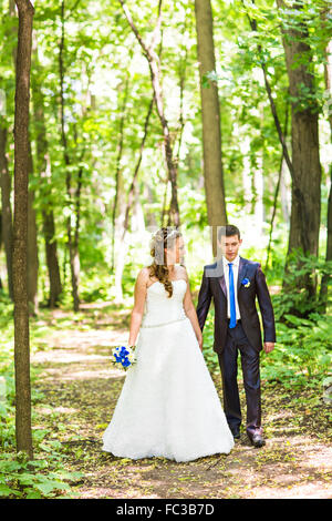 Couple nouvellement marié à pied sur les chemins du parc holding hands Banque D'Images