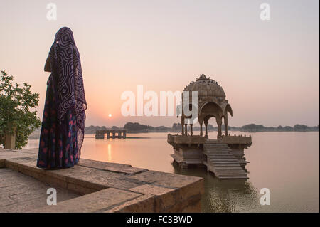 Les femmes locales standing infront de Gadi Sagar temple de Gadisar lake pendant le lever du soleil. Situé à Jaisalmer, Inde. Banque D'Images