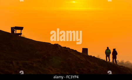 Camp Bratton, Westbury White Horse, Wiltshire, Royaume-Uni. Le 20 janvier, 2016. Météo britannique. Un magnifique coucher du soleil orange jette les marcheurs en bravant le silhouette, sous-glace conditions zéro sur la colline surplombant la ville de Westbury ci-dessous. L'ancien site du patrimoine anglais exposés abrite le célèbre cheval blanc craie et de gravure a été couvert dans une couverture de givre pour une bonne partie de la journée. Credit : Wayne Farrell/Alamy Live News Banque D'Images