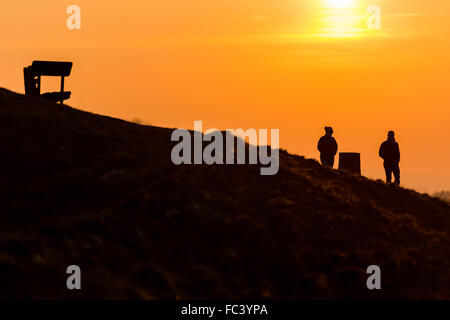 Camp Bratton, Westbury White Horse, Wiltshire, Royaume-Uni. Le 20 janvier, 2016. Météo britannique. Un magnifique coucher du soleil orange jette les marcheurs en bravant le silhouette, sous-glace conditions zéro sur la colline surplombant la ville de Westbury ci-dessous. L'ancien site du patrimoine anglais exposés abrite le célèbre cheval blanc craie et de gravure a été couvert dans une couverture de givre pour une bonne partie de la journée. Credit : Wayne Farrell/Alamy Live News Banque D'Images
