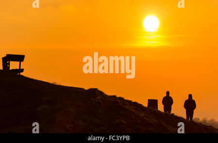 Camp Bratton, Westbury White Horse, Wiltshire, Royaume-Uni. Le 20 janvier, 2016. Météo britannique. Un magnifique coucher du soleil orange jette les marcheurs en bravant le silhouette, sous-glace conditions zéro sur la colline surplombant la ville de Westbury ci-dessous. L'ancien site du patrimoine anglais exposés abrite le célèbre cheval blanc craie et de gravure a été couvert dans une couverture de givre pour une bonne partie de la journée. Credit : Wayne Farrell/Alamy Live News Banque D'Images