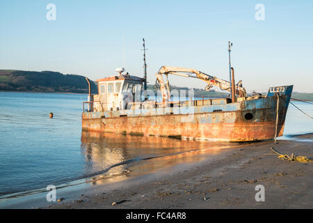 Ferryside Plage, Carmarthenshire, Pays de Galles, UK.Rusty,la rouille bateau amarré sur la plage au coucher du soleil, le coucher du soleil,Carmarthenshire, Pays de Galles au Royaume-Uni. Banque D'Images