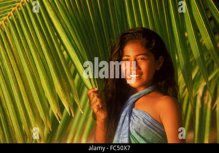 Fille polynésienne en face de feuilles de palmier vert sur les Îles Cook au coucher du soleil la lumière Banque D'Images