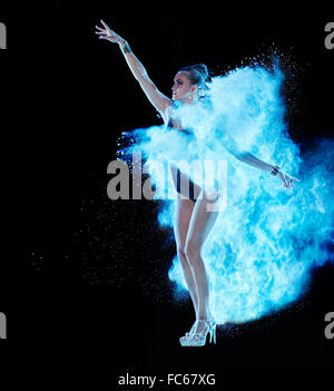 Jeune femme sautant en bleu nuage de poudre Banque D'Images