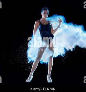 Jeune femme sautant en bleu nuage de poudre Banque D'Images