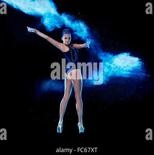 Jeune femme sautant en bleu nuage de poudre Banque D'Images