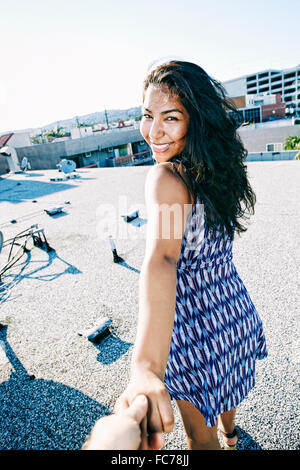 Hispanic woman pulling part on urban rooftop Banque D'Images