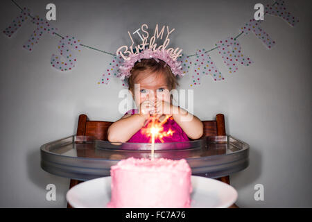 Caucasian baby girl admiring birthday cupcake Banque D'Images