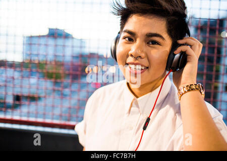 Asian woman listening to headphones outdoors Banque D'Images