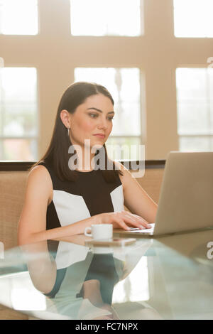 Hispanic businesswoman using laptop in office Banque D'Images