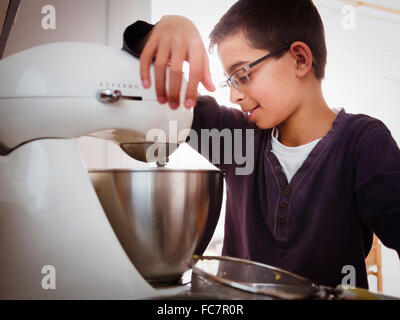 Mixed Race boy baking in kitchen Banque D'Images