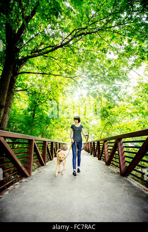 Caucasian woman walking dog on bridge Banque D'Images