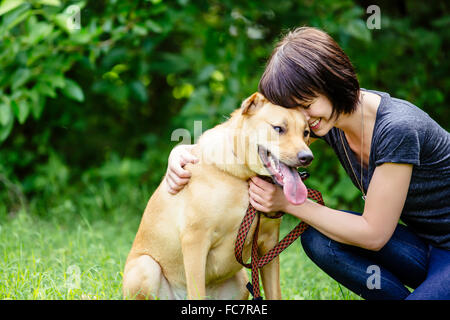 Caucasian woman petting dog in field Banque D'Images