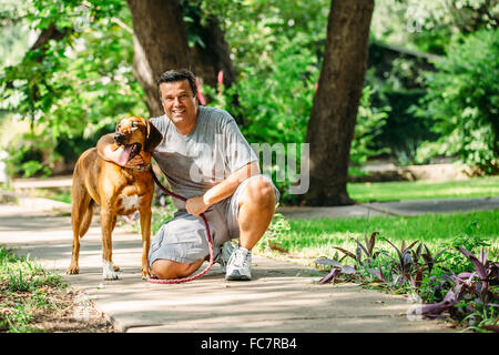 Caucasian man petting dog on sidewalk Banque D'Images