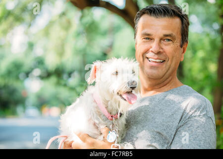 Caucasian man petting dog outdoors Banque D'Images