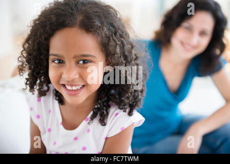 Mère et fille souriante sur canapé Banque D'Images