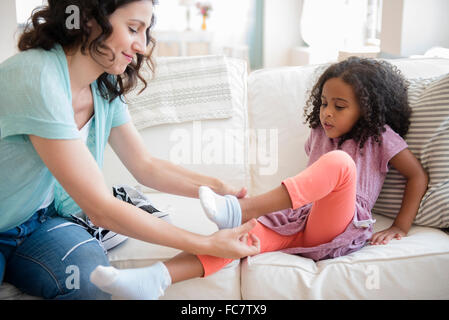 Mother helping daughter mis sur chaussettes Banque D'Images