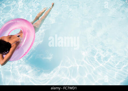 Caucasian woman floating in swimming pool Banque D'Images