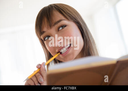 Mixed Race woman chewing-crayon et lecture Banque D'Images