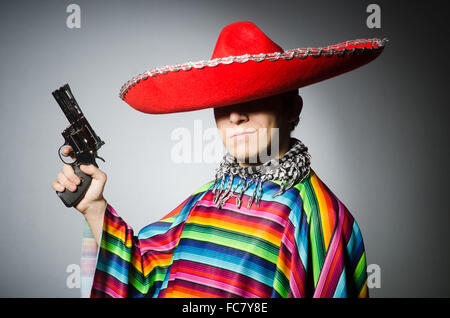 L'homme, dans des poncho mexicain holding handgun contre gray Banque D'Images