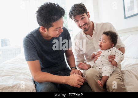 Les pères gays jouant avec son bébé sur le lit Banque D'Images